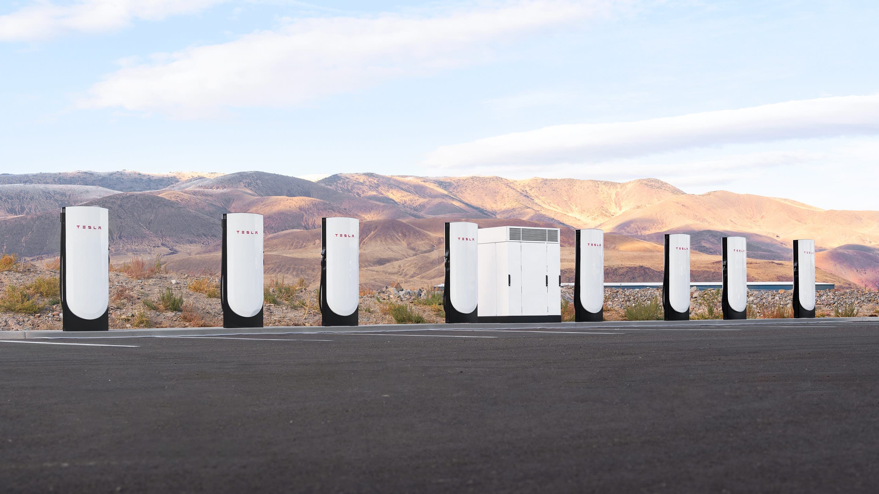 Rangée de Superchargeurs Tesla sur une route, symbole du réseau de recharge rapide de la marque