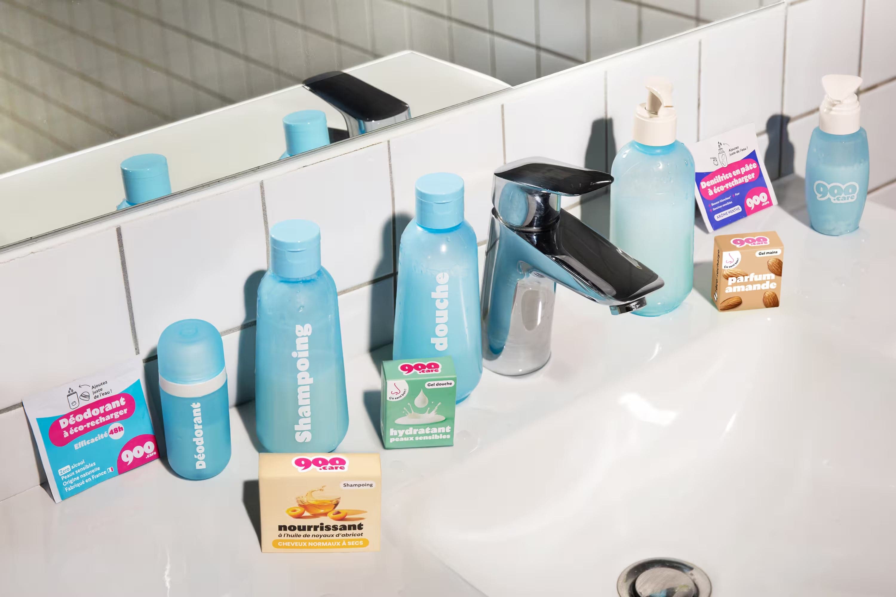 Flacons rechargeables 900.care et recharges de gel douche, shampoing, dentifrice, déodorant et gel mains sur un lavabo