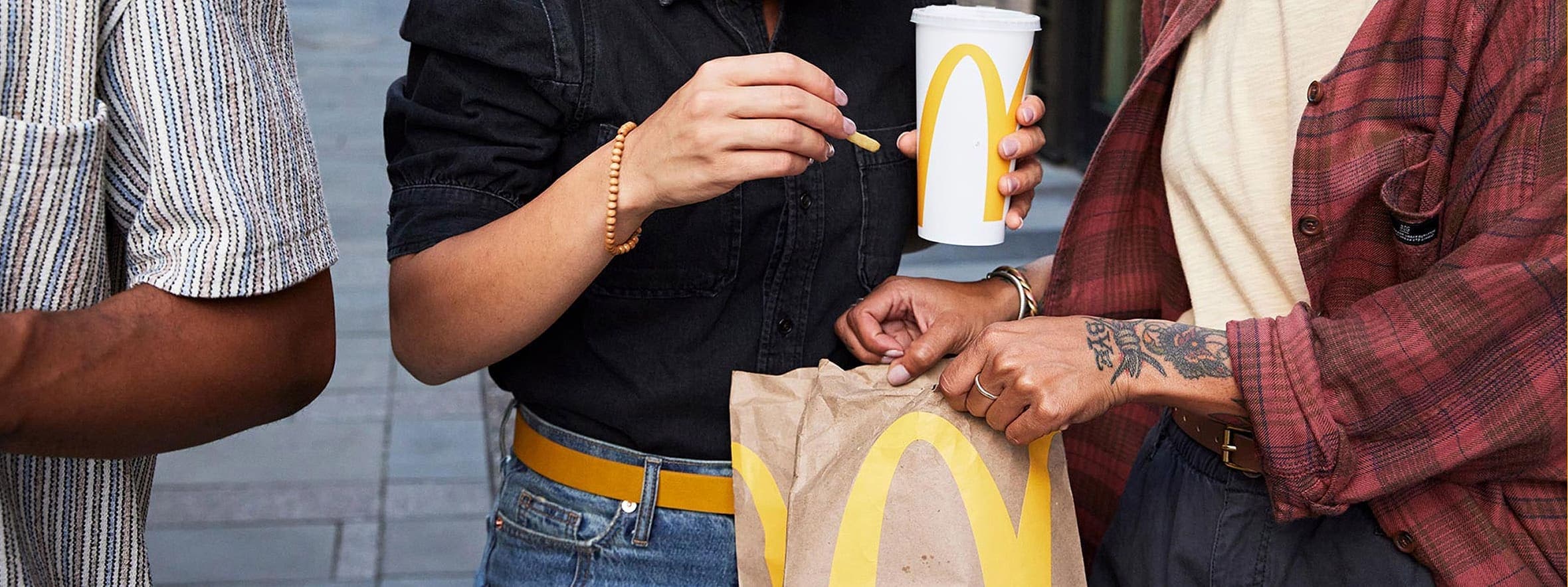 Trois clients partageant une commande McDonald's devant un restaurant