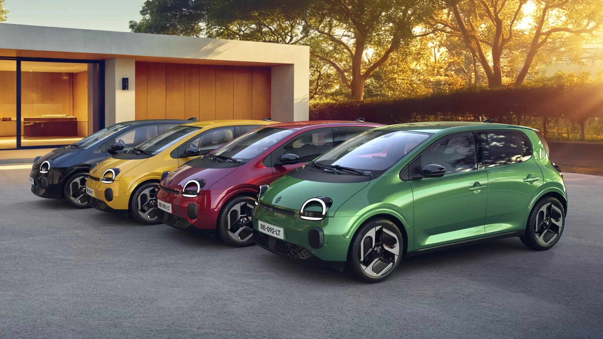Renault Twingo E-Tech electric en quatre couleurs devant une maison moderne
