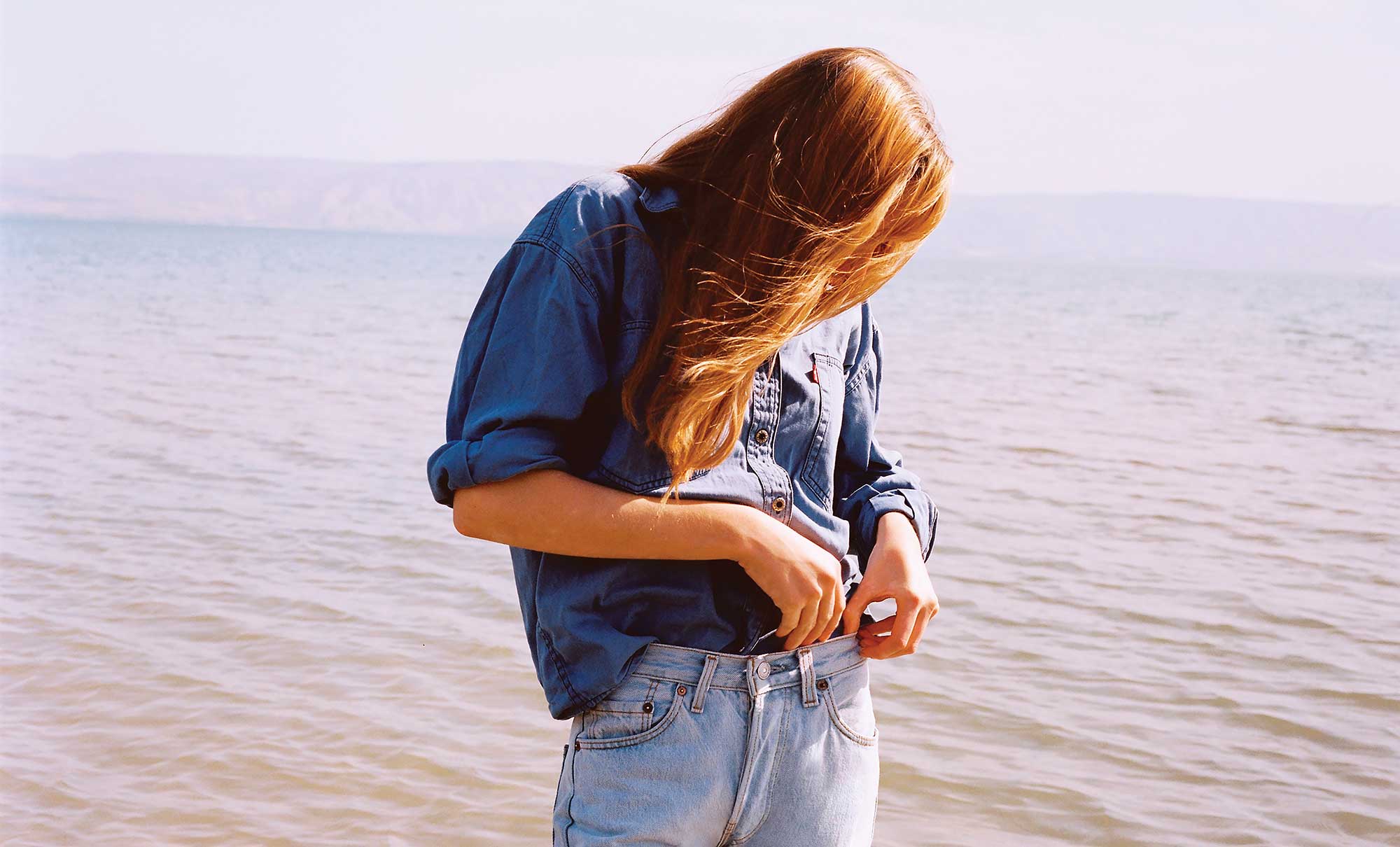 Personne portant une chemise et un jean Levi's au bord de la mer dans un visuel officiel consacré à la stratégie eau
