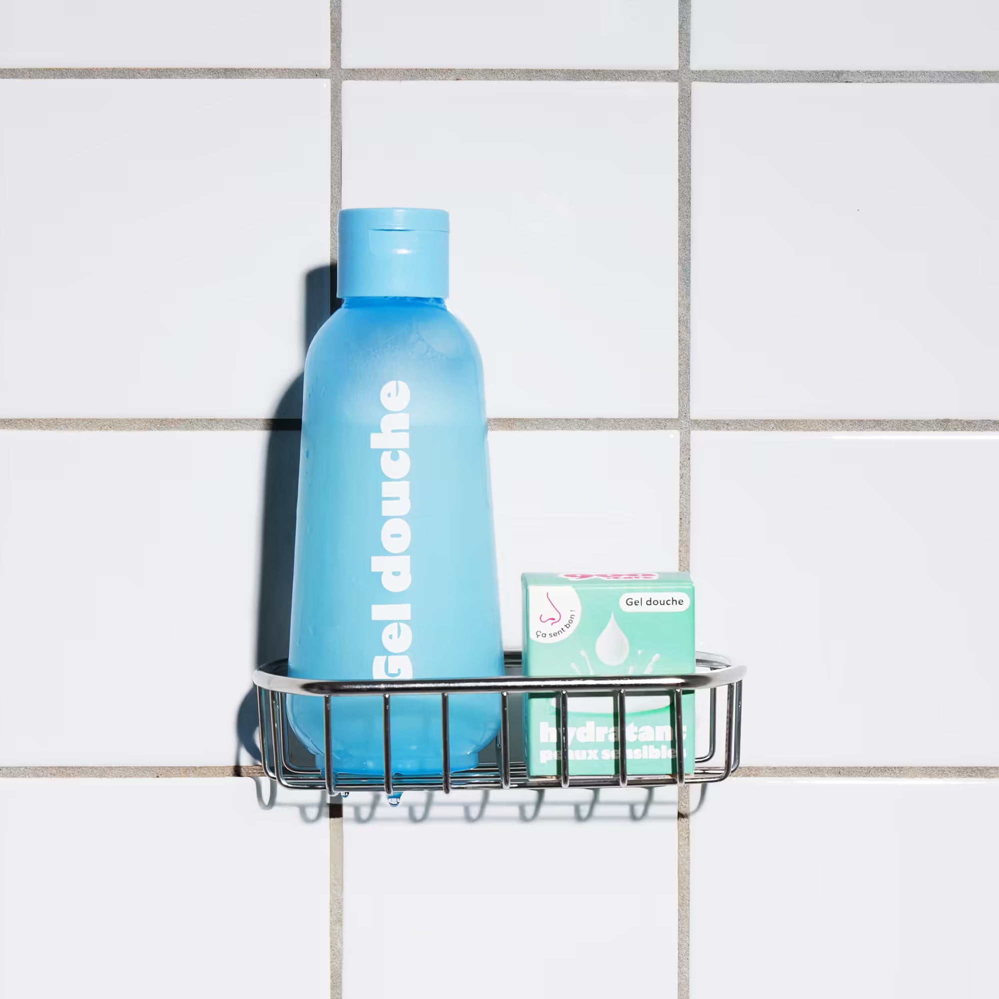 Flacon bleu de gel douche rechargeable 900.care avec sa boite de recharge dans une douche