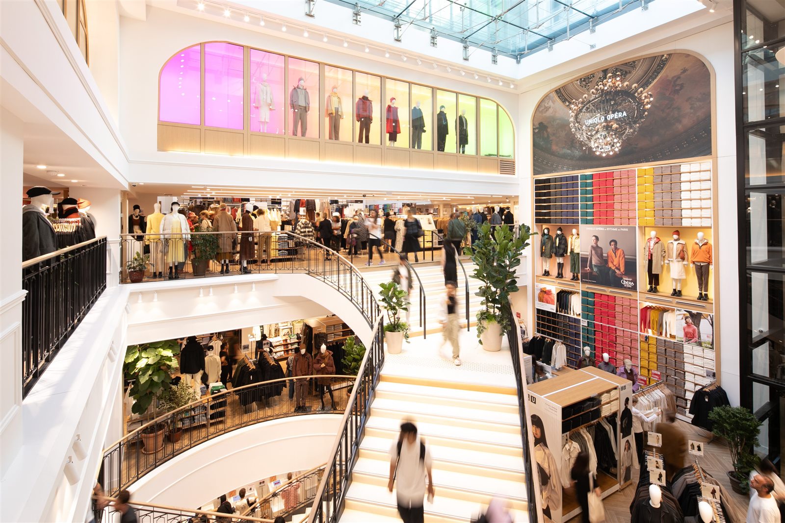 Intérieur du magasin UNIQLO Opéra avec escaliers, collections et murs de basiques colorés